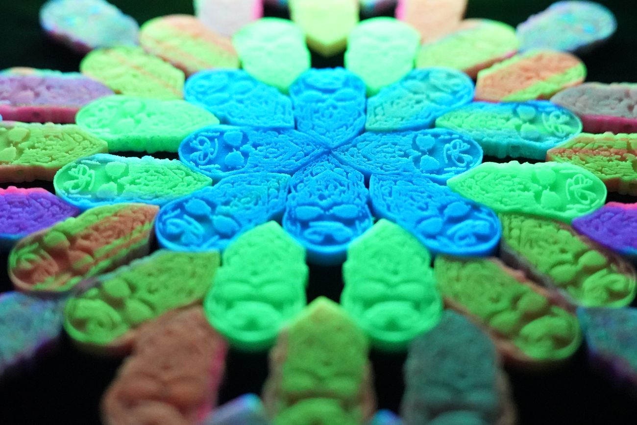 Glow-in-the-dark 3D printed kandi beads arranged in a mandala